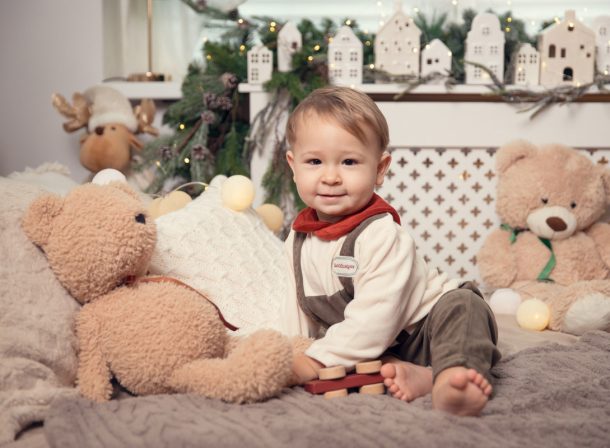 Bebeluș zâmbind printre ursuleți de pluș în decorul festiv de Crăciun Kinder Studio